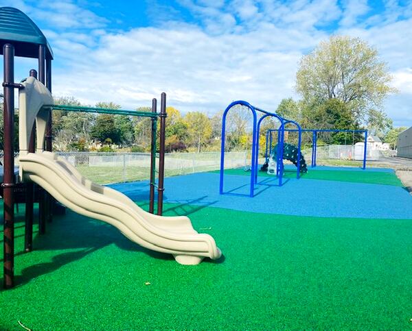 Tan playground on green rubber with swings